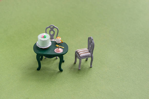 This scene features a small green table with a cake, plates, and utensils. A single chair accompanies the table, all set against a vibrant green backdrop that adds a playful touch.