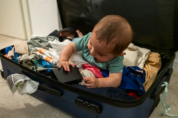 istock baby lying on suitcases playing with clothes from luggage 2236134021