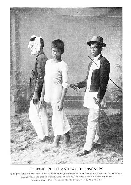Alleged criminals are tied with a rope when arrested for a policeman in the Philippine Islands, an archipelago in the Pacific Ocean. Photograph engraving published 1898. Copyright expired; artwork is in Public Domain.