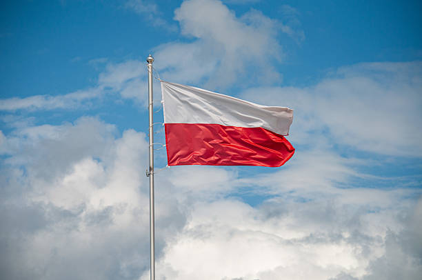 the Polish flag against a blue sky and clouds