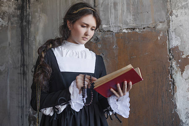 istock Religious sister reads prayer book while holding rosary in historic monastery. 2236149326