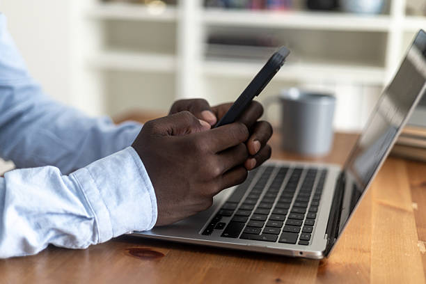 istock Man hands holding mobile phone, distracted from laptop work, procrastinating 2236151229