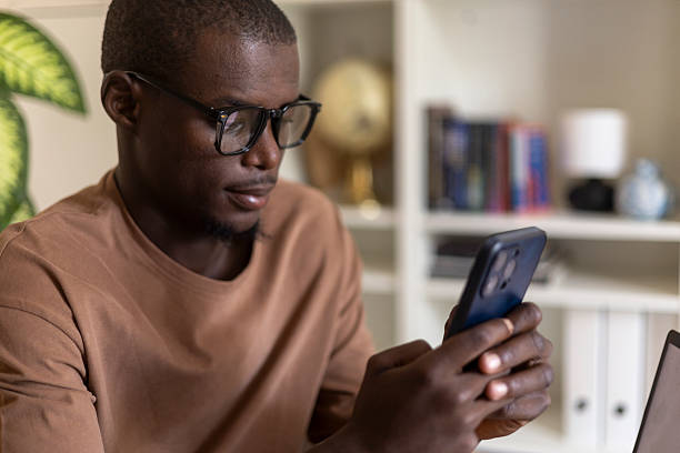 istock Black man wearing glasses checking mobile phone in an office setting 2236151424