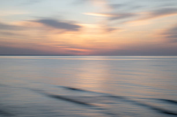 Soft abstract background featuring a blurred seascape with a pastel-colored sky. The image is rendered in a painterly, artistic style, creating a dreamy and tranquil atmosphere. Ideal for backgrounds, wallpapers, and creative design projects. High quality photo.