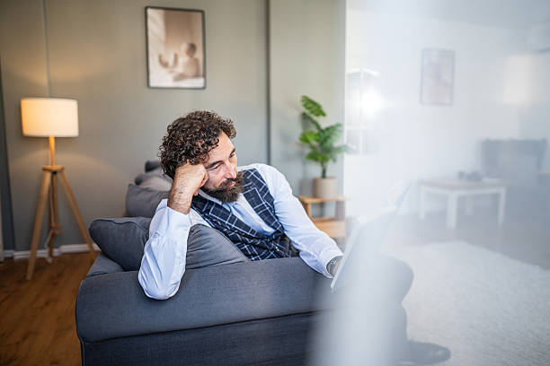 istock Stressed businessman working remotely on couch at home 2236154391