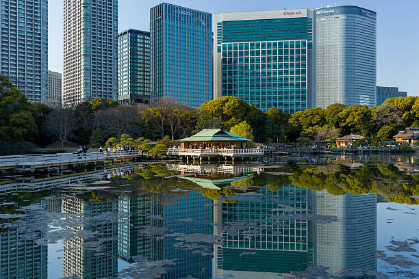 Traditional Japanese teahouse and pond in Hamarikyu Gardens with modern Tokyo skyline