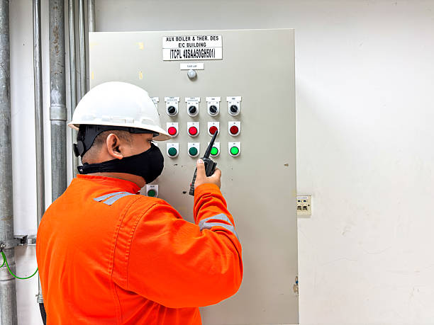istock Industrial worker wearing safety gear using a walkie-talkie and inspecting a control panel with buttons and switches in a plant for safety and efficiency maintenance process 2236159079