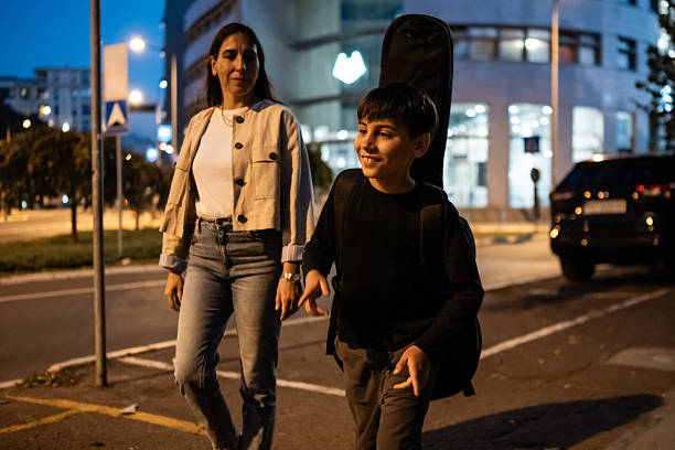 istock Mother son walking with guitar case at night 2236159751