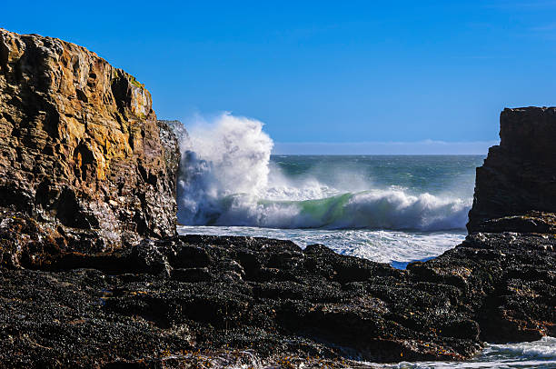 Ocean Waves crashing along California Coast, seen through the rock formation Davenport Crack.\n\nTaken at Davenport Crack, Davenport, California, USA