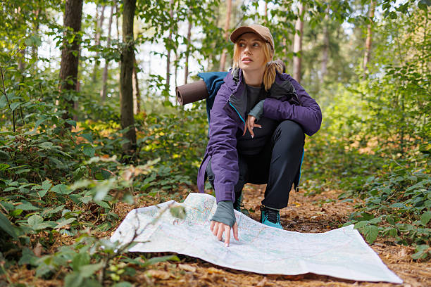 istock Young woman pointing at map while hiking in the forest 2236160411