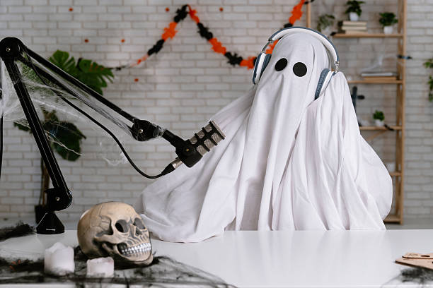 istock Funny ghost in a white sheet recording a podcast or blog 2236162403