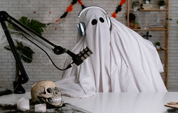 istock Funny ghost in a white sheet recording a podcast or blog 2236162525