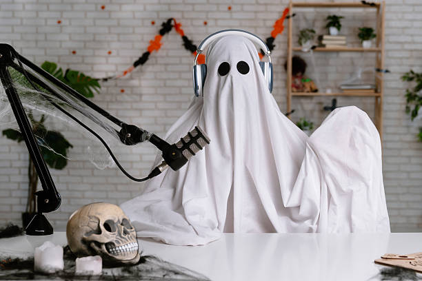 istock Funny ghost in a white sheet recording a podcast or blog 2236162668