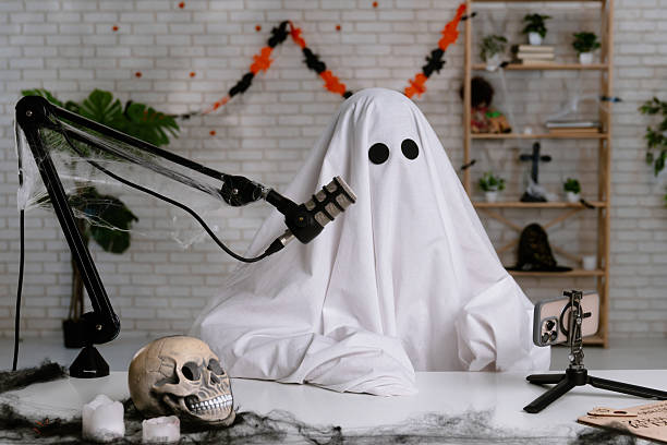 istock Funny ghost in a white sheet recording a podcast or blog 2236164344