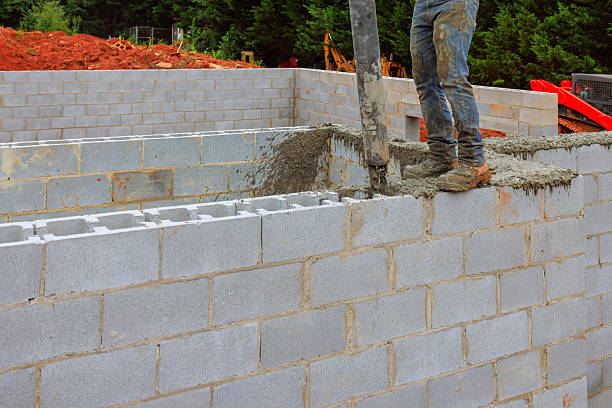 istock Construction worker pouring concrete into block wall at building site in afternoon 2236172995