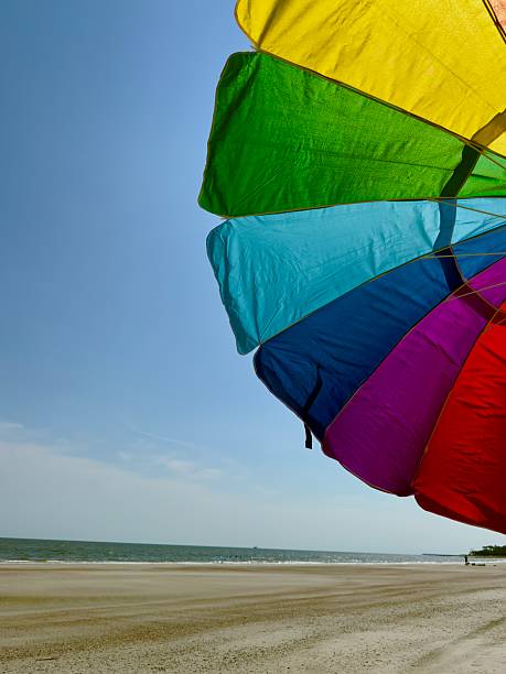 Brightly colored rainbow umbrella providing shade for sunbathers at Hunting Island State Park South Carolina