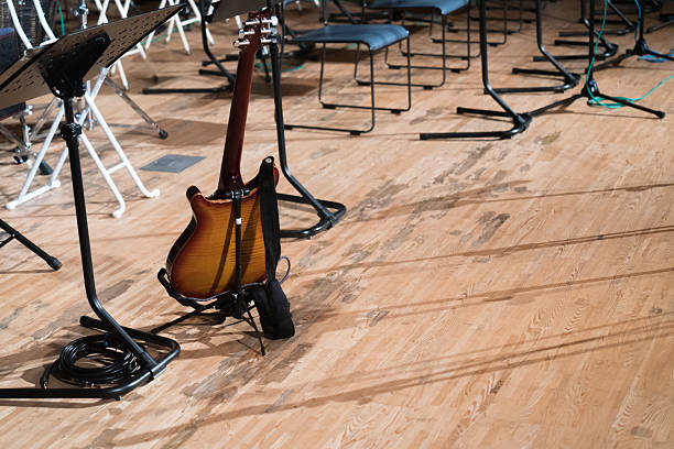 Concert view of acoustic electric guitar player with vocalist and rock band performing in a club, male musician guitarist on stage with audience in a crowded concert club hall arena, hands on guitar