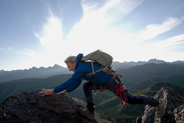istock Climber balances on mountain top at sunset 2236177075