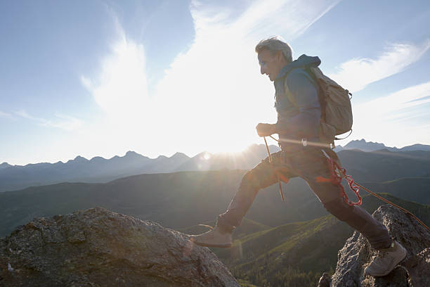 istock Climber jumps over gap on mountain top at sunset 2236177077