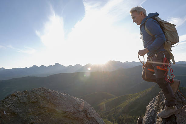 istock Climber jumps over gap on mountain top at sunset 2236177082
