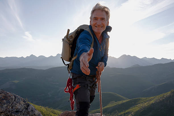 istock Climber on mountain top outstretching hand 2236177092