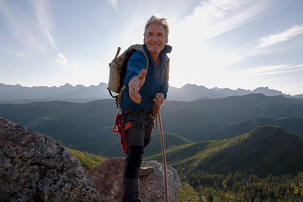 istock Climber on mountain top outstretching hand 2236177095