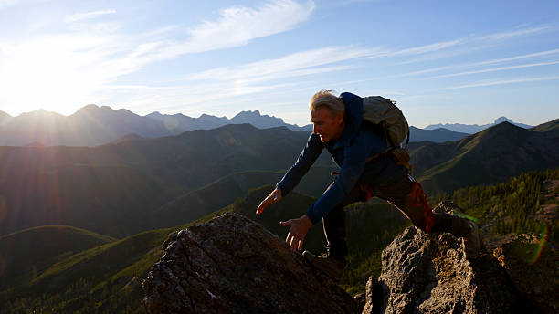 istock Climber jumps over gap on mountain top at sunset 2236177140