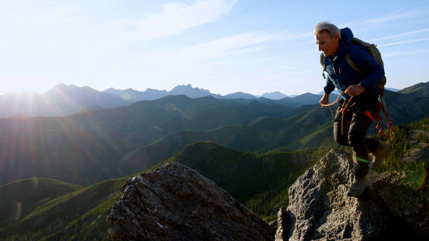 istock Climber jumps over gap on mountain top at sunset 2236177141