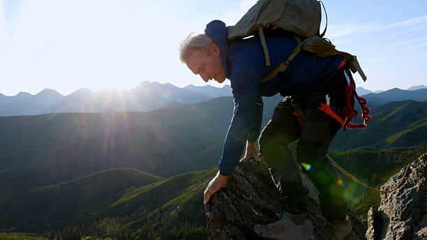 istock Climber jumps over gap on mountain top at sunset 2236177143