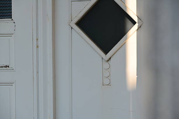 Traditional Taiwan door featuring diamond-shaped glass panel with white frame and decorative carved details, sunlight creating dramatic shadows.