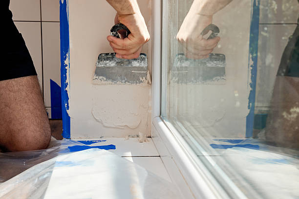 istock man with a spatula applying finishing putty on a window opening 2236187651