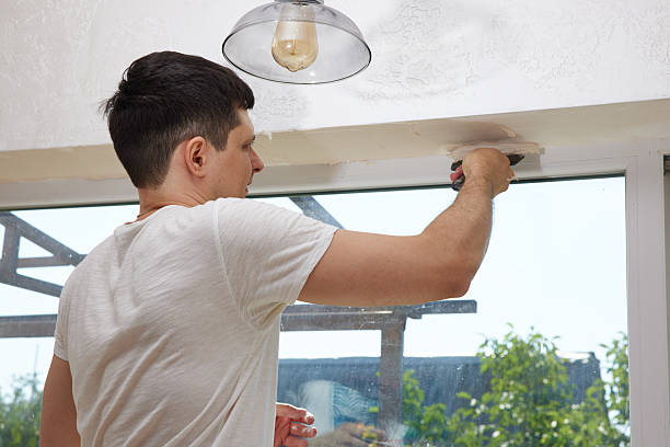 istock man with a spatula applying finishing putty on a window opening 2236187667