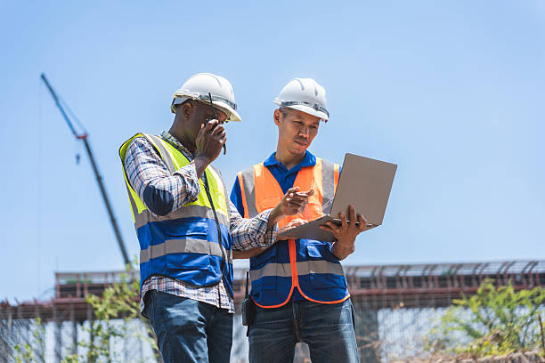istock Construction Engineers Using a Laptop and Walkie-Talkie on Site, Multicultural Team of Foreman Worker Planning with Digital Tools, Professional Project Managers at a Construction Site Reviewing Data 2236187773