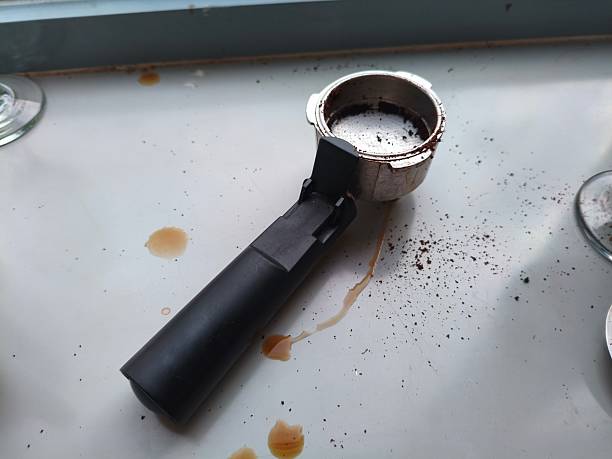 istock Coffee machine portafilter with used grounds and coffee spills on a white surface 2236188409