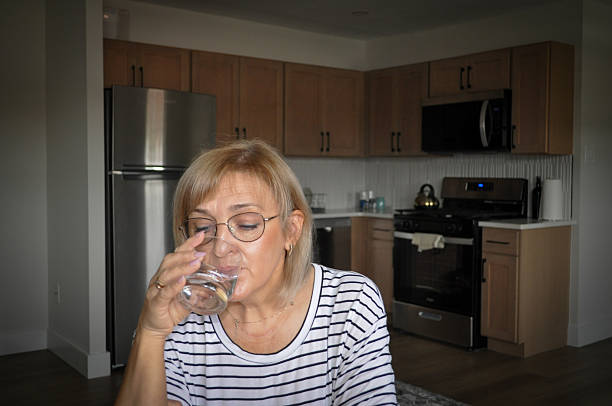 istock Woman drinking water in modern kitchen staying hydrated 2236190648