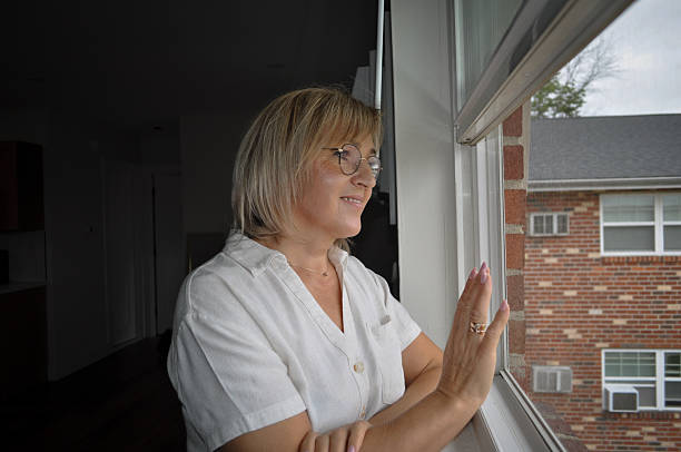 istock Woman with glasses smiling looking out window 2236190686