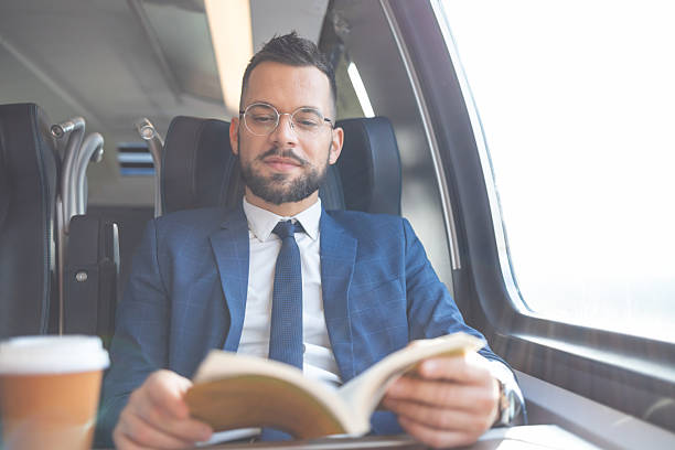 istock Young man is reading a book while traveling by train 2236192459