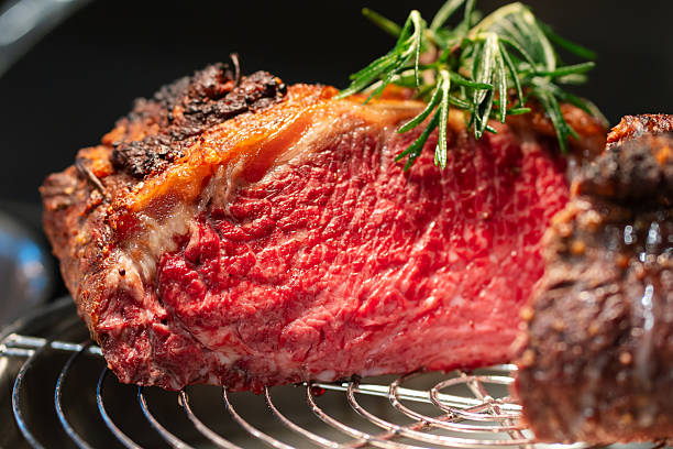 Medium-rare roast beef cut on display rack with herbs garnish.