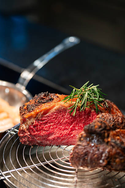 Medium-rare roast beef cut on display rack with herbs garnish.