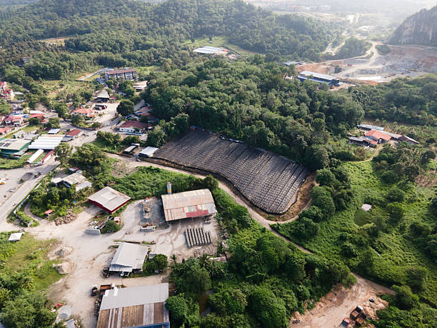 Aerial view of agricultural plantation covered with black shade nets surrounded by greenery and rural houses.