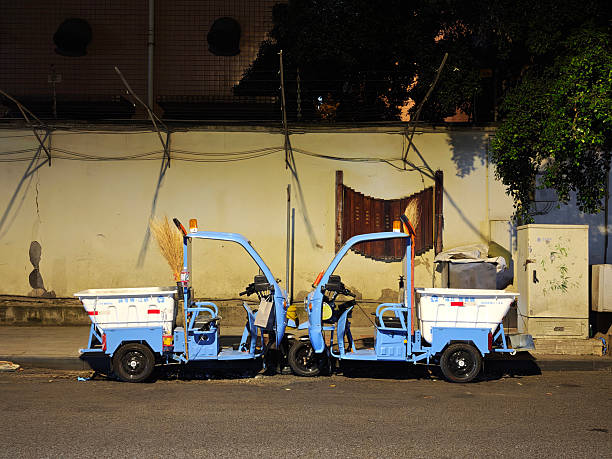 Two electric garbage tricycles parked at night along a street in Chengdu, Sichuan, China.