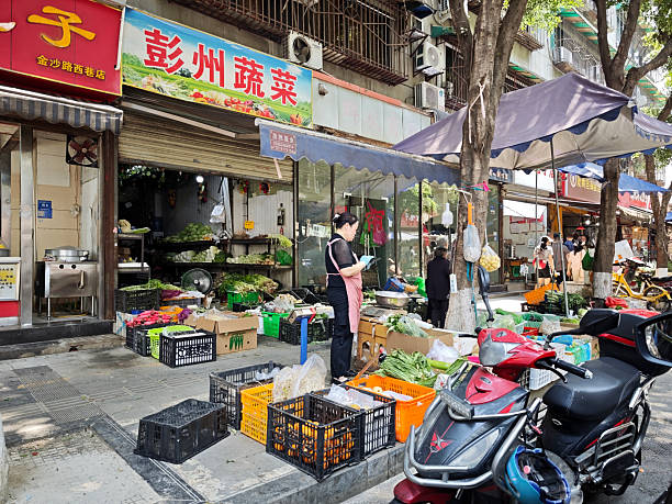 People walking by a grocery shop on a sidewalk in Chengdu, Sichuan, China.