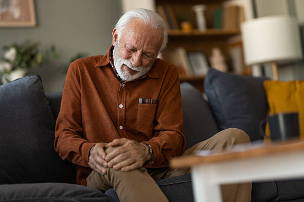 istock Unwell senior man having a knee pain while sitting on sofa at home. 2236200529