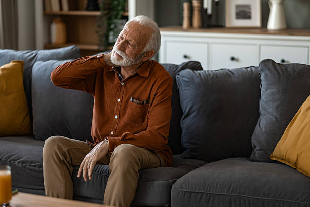 istock Unwell senior man having a neckache while sitting on sofa at home. 2236200536
