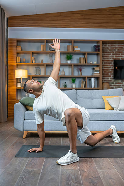 istock Athletic young african american  man doing exercises, working out muscles at home. Millennial man practicing domestic sports during covid quarantine, full length 2236200664