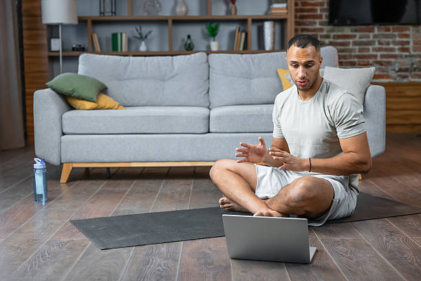 istock American professional trainer using laptop video call for training with group of people online workout at home. Online lessons for sports. Fitness man recording video on laptop in the living room. 2236200680