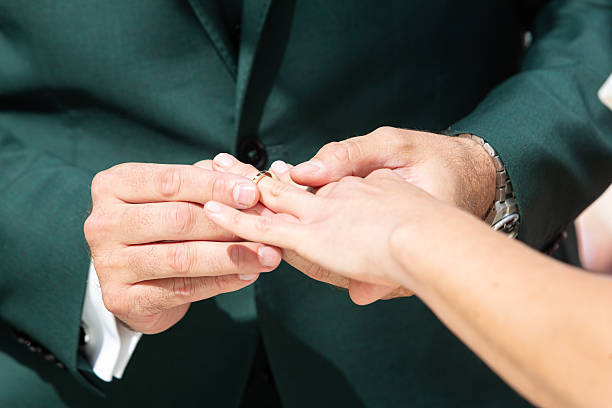 istock Groom placing wedding ring on bride's finger during ceremony 2236203907