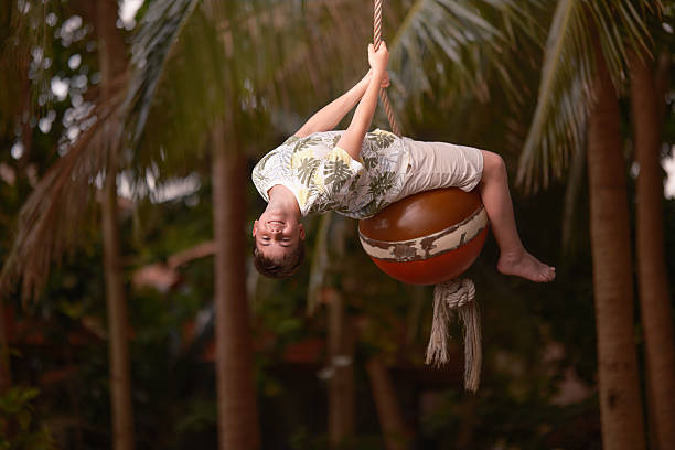 istock Playful boy having fun on a rope swing in nature. 2236208082