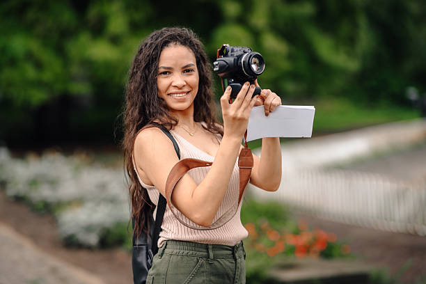 istock Young tourist holding camera and map in park 2236209090