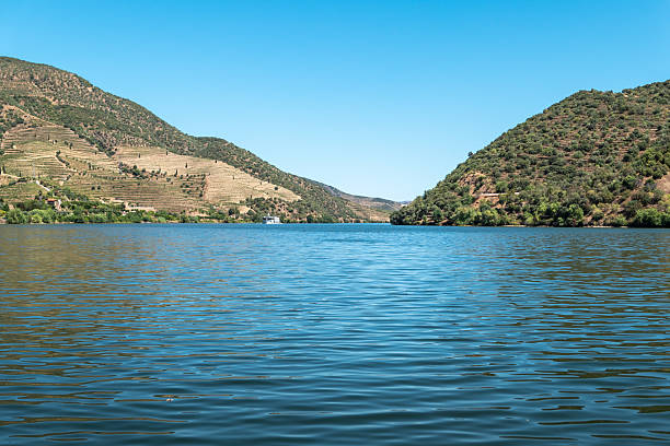 Passenger boat taking a trip on the Douro River amidst the mountainous landscape in Portugal